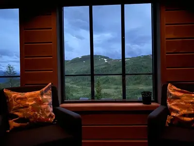 two chairs in front of a window with a mountain view at Høgerinden Lodge in Sogndal