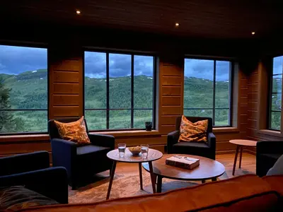 a living room with chairs and a table and windows at Høgerinden Lodge in Sogndal
