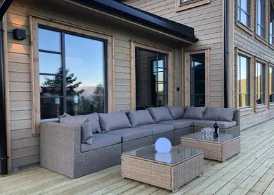 a patio with a couch and tables on a building at Høgerinden Lodge in Sogndal