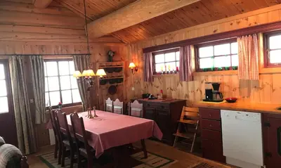 a kitchen with a table and chairs in a cabin at Berghstua - Natrudstilen på Sjusjøen in Sjusjøen