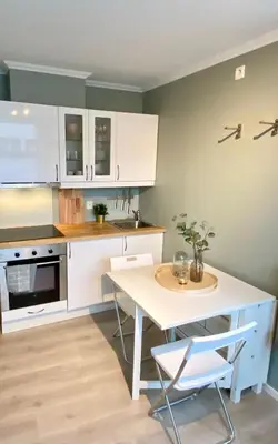a kitchen with white cabinets and a table with chairs at Apartment «Ladegården» in Bergen in Bergen