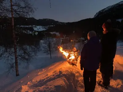 two people standing next to a fire in the snow at Kultan in Åmotsdal