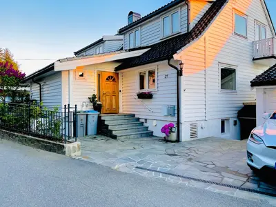 a white house with a yellow door and a driveway at Floien City House -free parking in Bergen