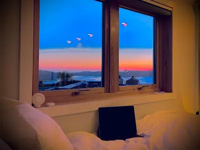 a bedroom with a window with a view of the sunset at Floien City House -free parking in Bergen