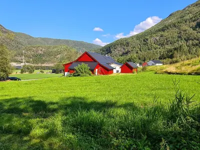 a red barn in a field with mountains in the background at Jondal Nice apartment with bed linen incuded in Jondal