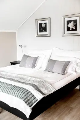 a bedroom with a large white bed with two pillows at Moens Motell in Fiskå