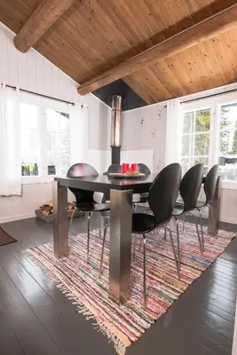 a dining room with a table and chairs on a rug at Nærglimt - cabin by the lake Næra in Ringsaker