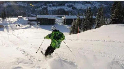 a man is skiing down a snow covered slope at Fin leilighet ca 30 min med bil til Hunderfossen in Favang
