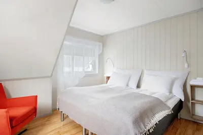 a bedroom with a white bed and a red chair at Aurland Guesthouse in Aurland
