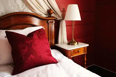 a bed with a red pillow and a lamp on a table at Sylte Hotell, Valldal in Valldal