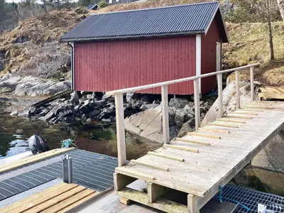 a dock with a red building with stairs in the water at 8 person holiday home in Halsanaustan-By Traum in Korsnes