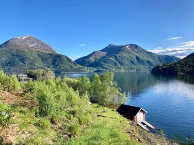 a small house on the shore of a lake with mountains at 8 person holiday home in Halsanaustan-By Traum in Korsnes