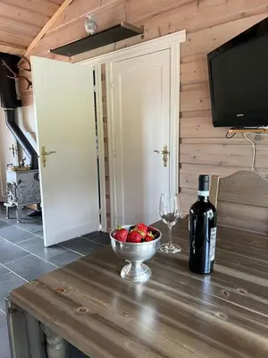 a table with a bowl of strawberries and a bottle of wine at Beitostølen sentralro in Beitostøl