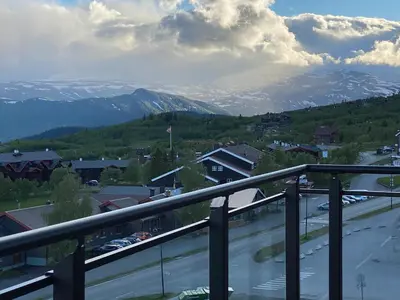 a view from a balcony of a town with snow covered mountains at Riddertunets moderne in Beitostøl