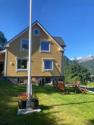 a house with two chairs and a table in the yard at Nesje Gardstun in Oppstryn