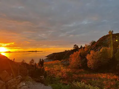 a sunset on the shore of a body of water at Ytterland Apartments in Ålesund