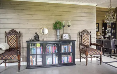 a room with two chairs and a book shelf with books at Lovely Home In Vossestrand With Wifi in Vossestrand