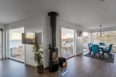 a living room with a fireplace and a table with chairs at Runde Panorama - Ørneredet in Runde