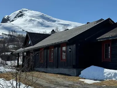 a house with a snow covered mountain in the background at Tyinkrysset panorama in Tyinkrysset
