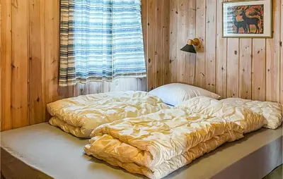 a bed in a room with a wooden wall at Nice Home In Hovden I Setesdalen in Hovden