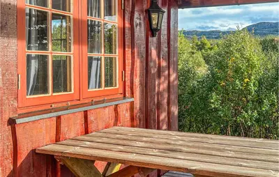 a wooden bench on the side of a house with a window at Nice Home In Hovden I Setesdalen in Hovden