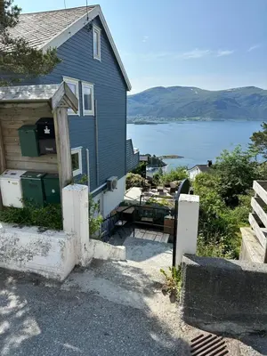 a blue house with a view of a body of water at Great place with a stunning view of the mountains and the fjord in Ålesund