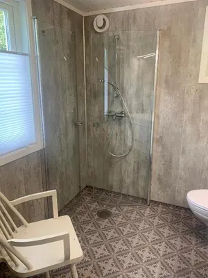 a bathroom with a shower and a toilet and a chair at Engen Gård in Innfjorden