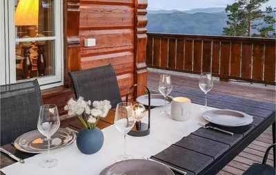 a table with plates and wine glasses on a deck at Lovely Home In Tuddal With Jacuzzi in Tuddal