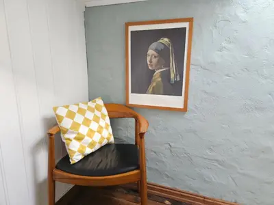 a chair with a pillow next to a painting of a woman at Sigurd's Loft in Vossevangen