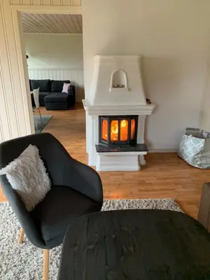 a living room with a black chair and a fireplace at Feriehus med utsikt til fjord og fjell in Gvammen