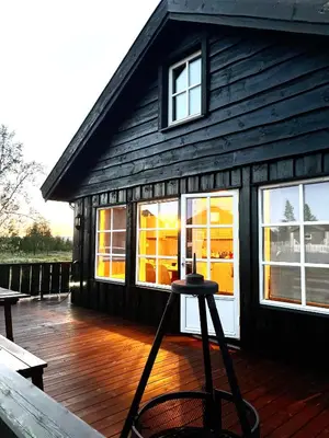 a building with windows and a stool on a deck at Sanderstølen Hytte in Tisleidalen