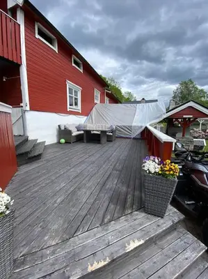 a wooden deck with a bench and a red building at Eidsviklaaven in Ålesund