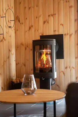 a fireplace in a room with a table and a coffee table with a fire at Gaustablikk Hytte - MountainView in Gaustablikk
