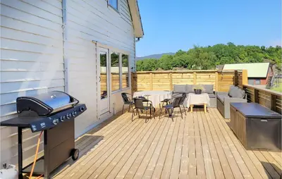 a deck with a grill and a table and chairs at Nice Home In Fitjar With House Sea View in Fitjar