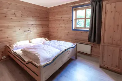 a bedroom with a bed in a wooden wall at Bakkebyvegen 1D in Trysil