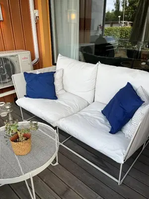 a white couch sitting on a porch with blue pillows at Sentralt 10 minutt med buss til Trondheim Sentrum in Trondheim