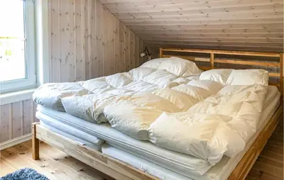 a large bed with white sheets on it in a room at Cozy Home In Brøttum With Kitchen
