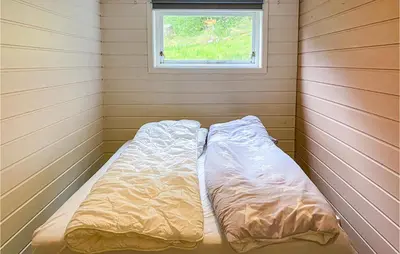 a bed in a corner of a room with a window at 1 Bedroom Amazing Apartment In Øydegard in Aspa