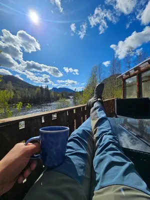 a person with their feet up on a fence holding a coffee cup at Holiday Rooms in Gol