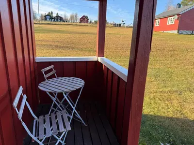 two chairs and a table on a porch with a field at Skåbu Camping in Skåbu