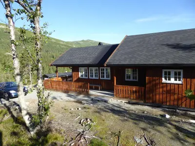 a large wooden house with a car parked in front of it at Ny hytte i flott turterreng in Nore