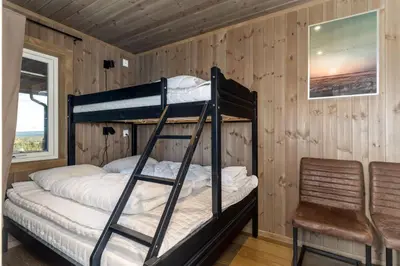 a bedroom with two bunk beds and a chair at Koselig leilighet med ski in ski out på Golsfjellet in Gol