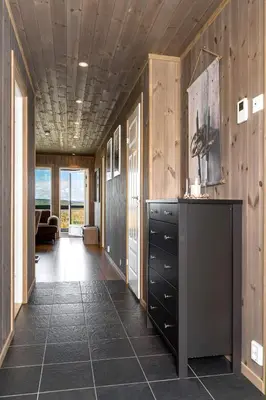 a hallway with wooden walls and a kitchen with a counter at Koselig leilighet med ski in ski out på Golsfjellet in Gol