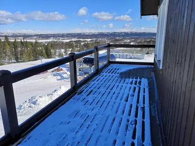 a bench on the balcony of a house in the snow at Koselig leilighet med ski in ski out på Golsfjellet in Gol