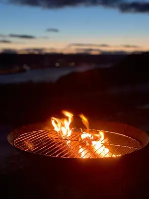 a fire pit with flames in it at sunset at Landlig beliggenhet med flott utsikt over Mjøsa in Ulven