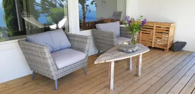 a porch with a table and two chairs and a table with flowers at Relaxing place on Godøya in Godøy