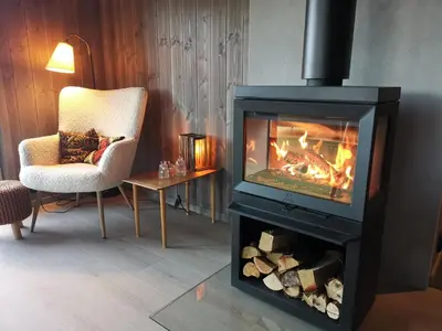 a living room with a fireplace and a chair at Flott hytte sentralt i Hallingdal in Ål