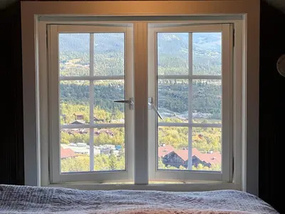 a bedroom with two large windows with a view at Bjødnabakkens fjellutsikt in Beitostøl