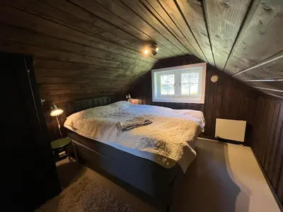 a small bedroom with a bed in a wooden room at Bjødnabakkens fjellutsikt in Beitostøl