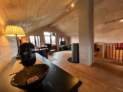 a living room with a wooden ceiling and a table at Stadionutsikten in Beitostøl